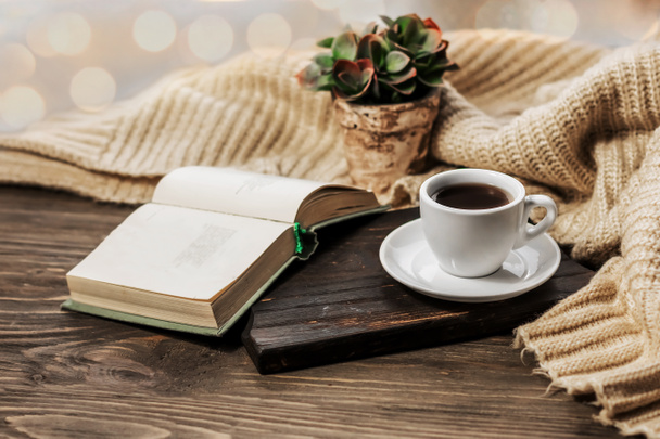 ベッドでコーヒー、ロマンチックな朝。木製のテーブルの上に本とコーヒーカップを開きます。ホーム居心地の良いインテリア、ライフスタイル。選択的焦点 - 写真・画像