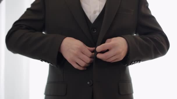 Pan młody zapinana kurtka, człowiek w garniturze zapina guziki na kurtce przygotowując się do wyjścia - Materiał filmowy, wideo