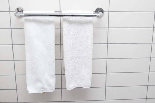 Heated towel rail on bathroom wall. White towels drying on a heated towel rail - Foto, afbeelding