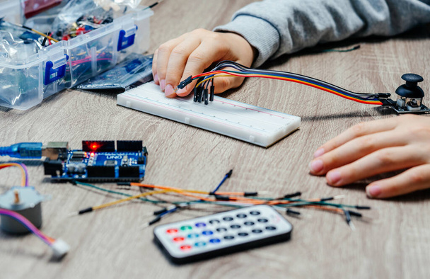 A child plugging cables to sensor chips while learning arduino coding and robotics - Foto, Imagem