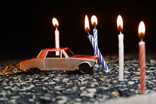 Toy car crashes into lit candles as bad luck birthday concept - Foto, Imagen