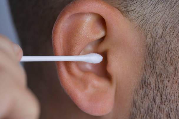 Closeup of man cleaning dirty ears with cotton swab or cotton stick - Фото, зображення