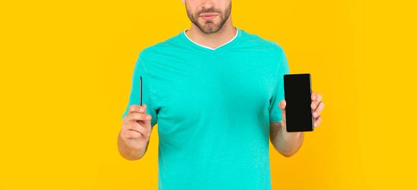 cropped young man presenting phone and stylus on yellow background, presentation - Fotó, kép