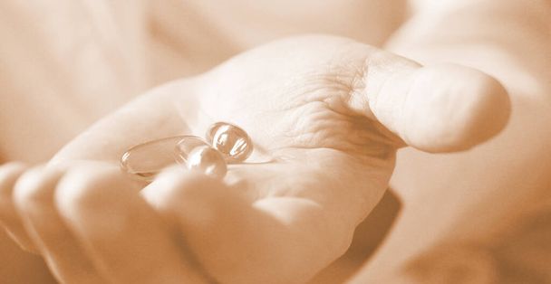 Lágy zselé tabletták Omega-3 olaj ömlött ki tabletta üveg közelkép iin idős nő kezét. Egészségügyi koncepció. Szelektív foocus. - Fotó, kép
