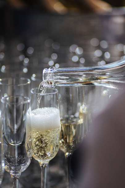 Офіціант вливає шампанське з пляшки в прозоре скло, бульбашки з напою
 - Фото, зображення