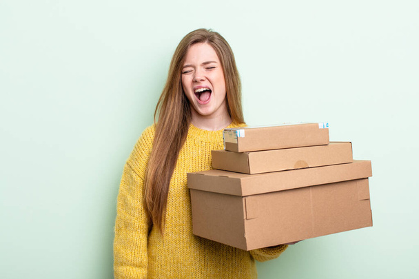 red hair woman shouting aggressively, looking very angry. packages boxes concept - Fotó, kép