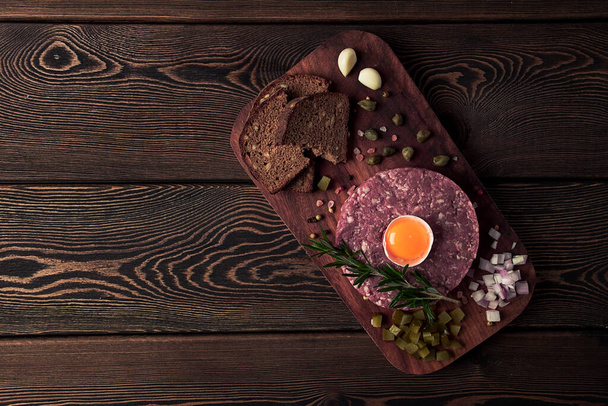 Beef tartare, with egg capers, gherkins and bread,toned, top view, close up, horizontal, no people, - Фото, зображення