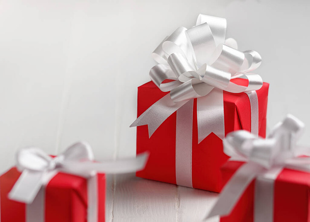 Rode geschenkdozen met witte strik op een witte tafelondergrond. - Foto, afbeelding