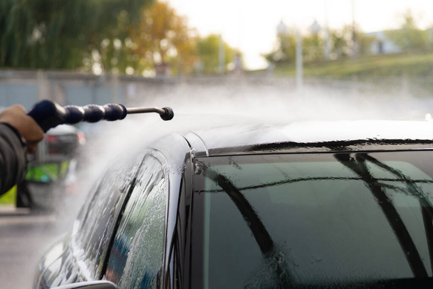 Washing a black car in the fresh air. Rinse the car with water. - Fotó, kép