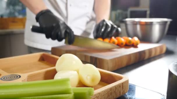 シェフはニンジンを切るためにナイフを使用します。木製のまな板に大きなオレンジニンジンを切断します。新鮮な野菜だ。健康食品、家庭料理、食事、ベジタリアンレシピ。4 kビデオ - 映像、動画