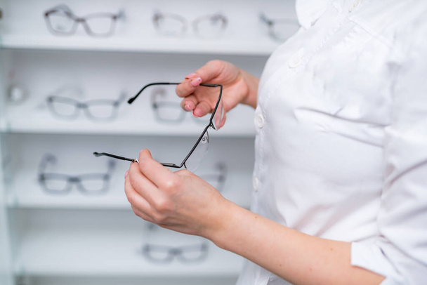 Optician, optometrist, oculist or eye doctor holding glasses and specs with new lenses. Professional eyesight specialist in clinic or shop with spectacles in hand. Bifocal or multifocal eyeglasses - Foto, Bild
