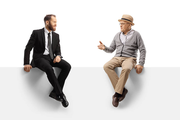 Homme âgé parlant à un homme d'affaires et assis sur un panneau isolé sur fond blanc - Photo, image