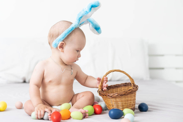 Portrait of a cute baby dressed in Easter bunny ears with a basket full of eggs - Foto, immagini