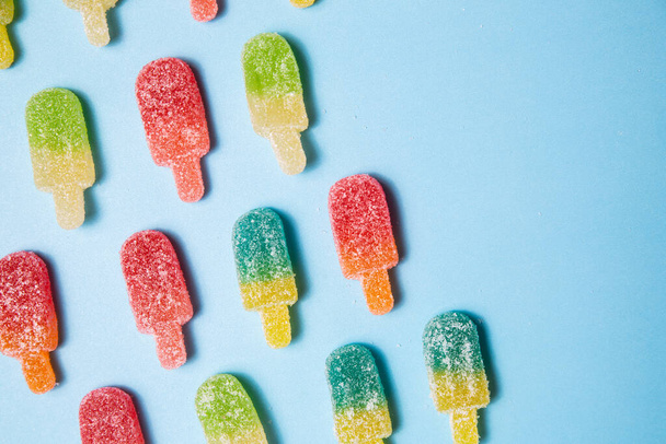 Sugary gummy popsicle candy pattern on blue - Photo, Image
