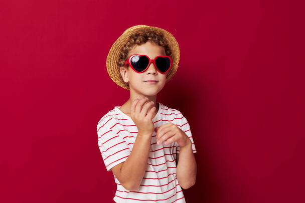 Güneş gözlüğü takan çocuk çocuksu bir şapka takıyor. - Fotoğraf, Görsel