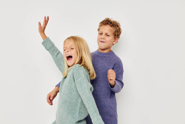 Boy and girl in multi-colored sweaters posing for fun light background - Foto, imagen