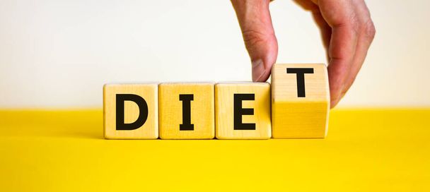 Diet instead die symbol. Doctor turns a wooden cube and changes the word die to diet. Beautiful yellow table, white background. Healthy lifestyle, dietology and diet instead die concept. Copy space. - Zdjęcie, obraz