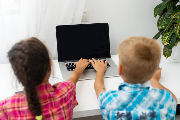 Cute children use laptop for education, online study, home studying, Boy and Girl have homework at distance learning. Lifestyle concept for home schooling. - Photo, Image