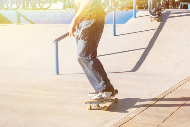 Skater boy skateboarding at skatepark ramp in sunny summer day in city. Active urban life. Urban subculture.  - Foto, Bild