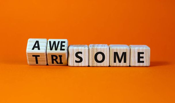 Awesome or trisome symbol. Turned wooden cubes and changed the concept word awesome to trisome. Beautiful orange table, orange background, copy space. Medical, awesome or trisome concept. - Zdjęcie, obraz