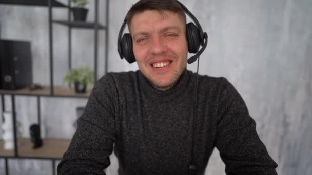 Happy smiling young man looking at camera and speaking. Agreeing with client during video call. Using modern communication technology - Felvétel, videó