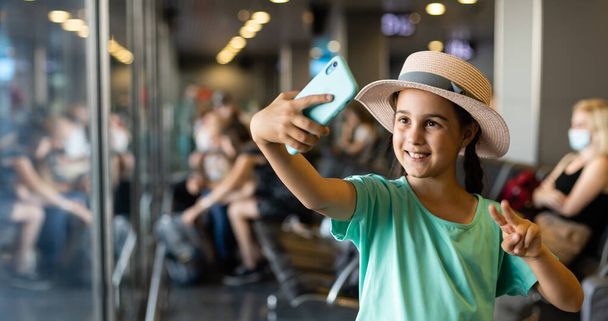 туризм, відпустка, дитинство і транспорт концепція усміхнена дівчинка з дорожньою сумкою, квиток і паспорт над аеропортом фону
. - Фото, зображення