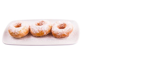 hausgemachter Donut mit Zuckerbelag auf weißem Teller vor weißem Hintergrund - Foto, Bild