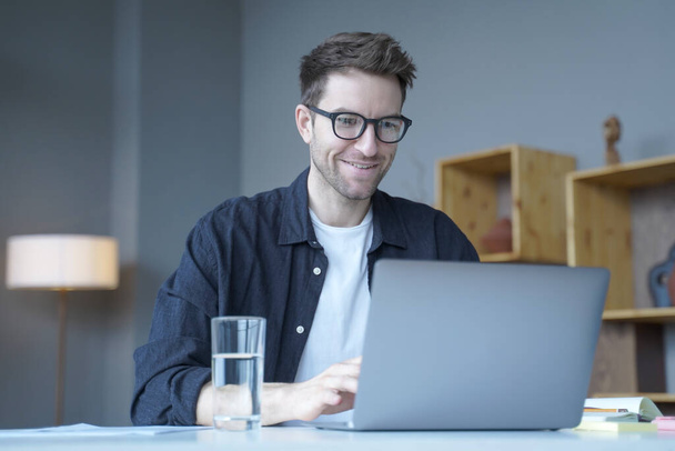 Young smiling businessman European financial consultant working remotely online from home office - Photo, Image