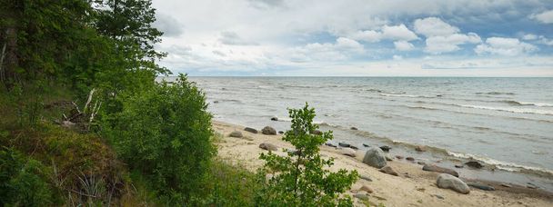 Panoramic aerial view of the rocky Baltic sea shore, pine forest. Summer. Gulf of Riga, Latvia. Dramatic sky, storm waves. Fickle weather. Vacations, travel destinations, ecotourism. Nature, seascape - Foto, Bild