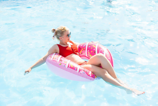 Özel villadaki havuzda donut lilo içen bir kadın. Şişme halka ve şilte. Yaz tatili cennet gibi. Yukarıdan yüksek görünüm - Fotoğraf, Görsel