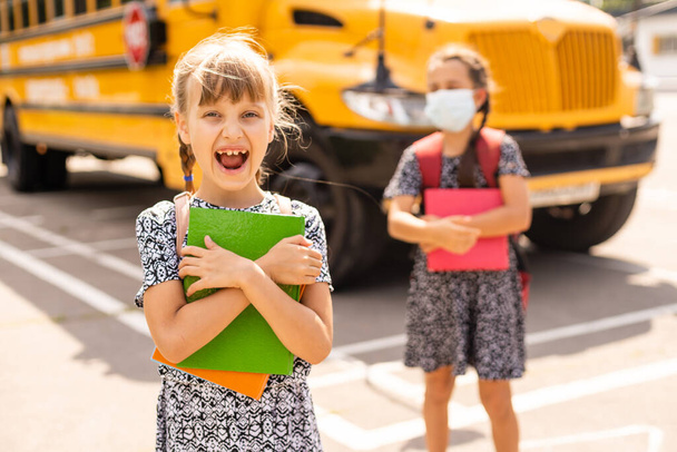 The schoolgirl puts on a mask to prevent colds and viruses. Medical concept. Back to school. Child going school after pandemic over. - Foto, Imagem