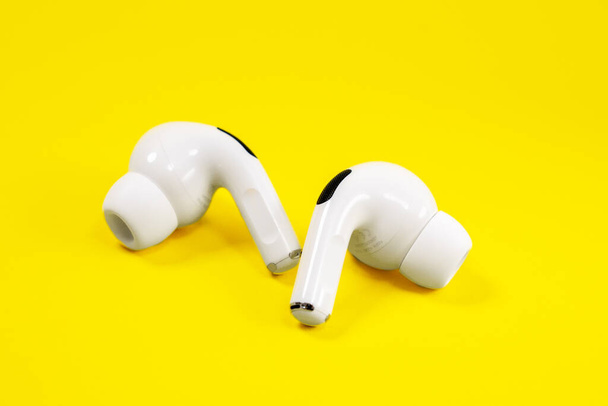 Rostov, Russia - July 06, 2020: Wireless headphones Apple AirPods Pro with soft, flexible silicone tapered tips on yellow background, copy space for advertising, close up. - Photo, Image