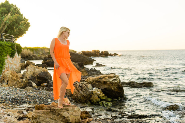 美しい女性のドレスで石の海のビーチ - 写真・画像