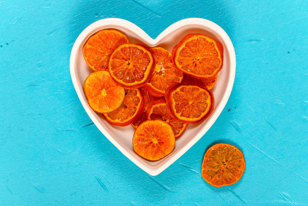 Сушені апельсинові скибочки в мисці у формі серця, що використовується для ароматних різдвяних прикрас
. - Фото, зображення