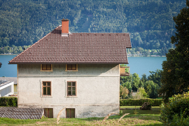 Selective blur on a typical austrian chalet on the ossiacher see, in Sattendorf, near Villach, in Carinthia, used for residential purposes and for hosting tourists in front of the main landmark of the region. - Valokuva, kuva