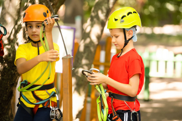 Child in forest adventure park. Kids climb on high rope trail. Agility and climbing outdoor amusement center for children. Little girl playing outdoors. School yard playground with rope way. - Foto, Imagem