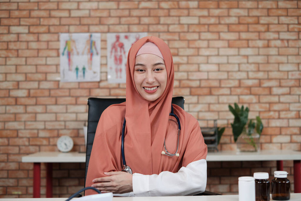 Portrait d'une belle femme médecin, belle musulmane en uniforme avec un stéthoscope, souriante et regardant la caméra dans la clinique de l'hôpital. Une personne qui possède une expertise en traitement professionnel. - Photo, image