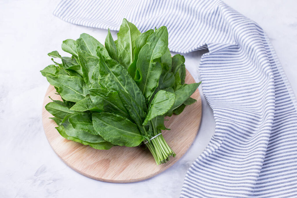 A bunch of fresh sorrel leaves on a light background with a napkin. Healthy greens for a healthy diet. Vitamins in natural products. - Foto, imagen