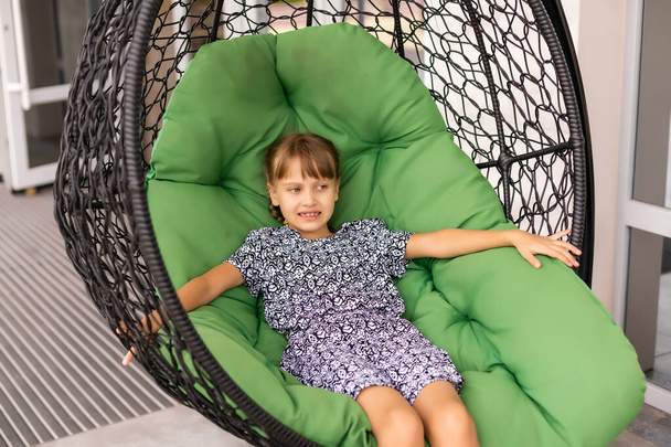 Petite fille assise sur une chaise cocon suspendu - Photo, image
