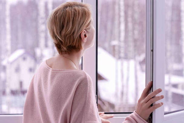 Eine Frau, die im Winter aus dem Fenster schaut - Foto, Bild