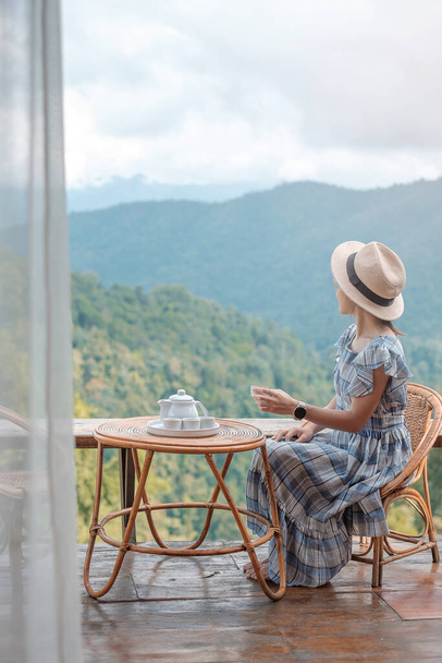 mujer bebiendo té y buscando vistas a la montaña, joven blogger estancia en casa de campo por la mañana.Viajes, vacaciones, viaje, viaje y concepto relajante - Foto, Imagen