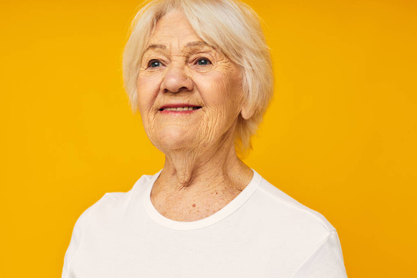 Photo of retired old lady in white t-shirt posing fun yellow background - Zdjęcie, obraz
