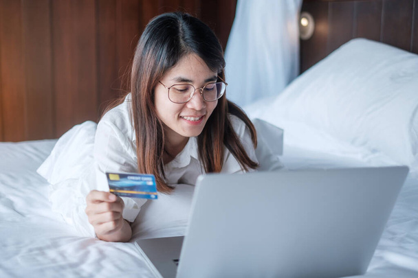 Kadın, sabah evde yatakta sipariş verirken online alışveriş için bilgisayar ve kredi kartı kullanıyor. teknoloji, ekommerce, dijital bankacılık çevrimiçi ödeme ve apartman konsepti - Fotoğraf, Görsel