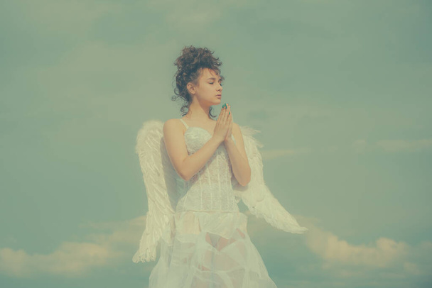 Valentines angel teen praying. Angel teen in heaven. Teenage angel girl with wings, copy space on sky. - Photo, image