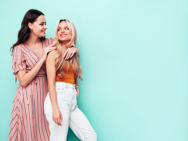 Two young beautiful smiling brunette hipster female in trendy summer clothes. Sexy carefree women posing near blue wall. Positive models having fun. Cheerful and happy - Fotoğraf, Görsel