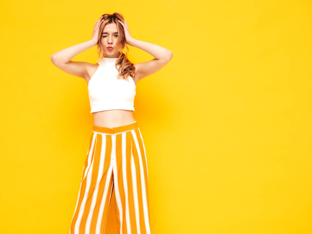 Portrait of young beautiful smiling blond female in trendy summer clothes. carefree woman posing near yellow wall in studio. Positive model having fun indoors. Cheerful and happy - Fotografie, Obrázek
