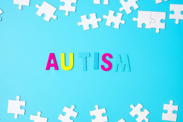 Текст AUTISM з білими шматочками головоломки на синьому фоні. Концепції здоров'я, розлад аутистичного спектру та Всесвітній день аутизму
 - Фото, зображення