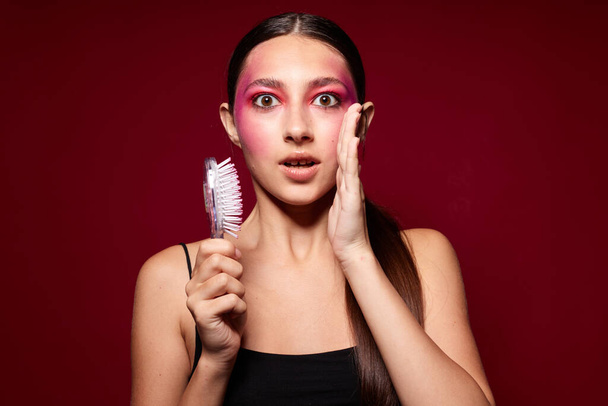 Beauty fashion female pink face makeup posing attractive look with a comb pink background unaltered - Fotó, kép
