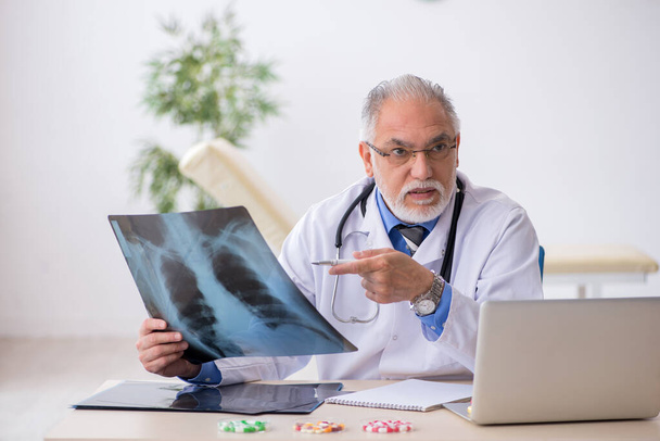 Old male doctor radiologist working in the clinic - Foto, imagen