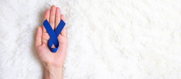 Marzo mes de conciencia sobre el cáncer colorrectal, Hombre con cinta azul oscura para apoyar a las personas que viven y enferman. Salud, esperanza y concepto del Día Mundial del Cáncer - Foto, Imagen